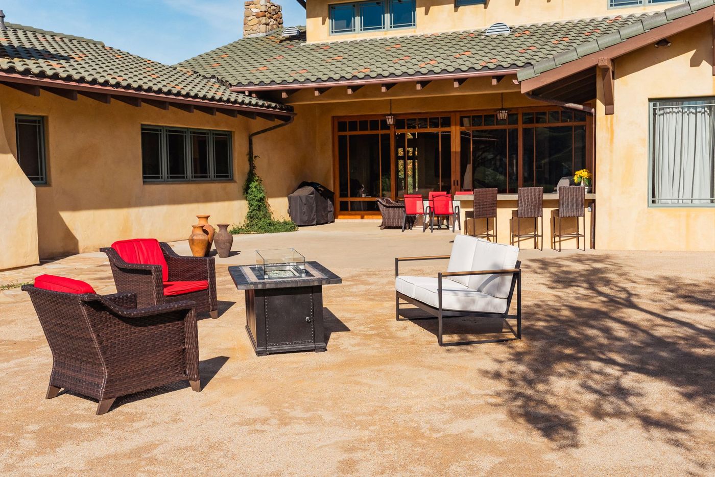 Custom outdoor living patio in San Luis Obispo featuring modern lounge seating and a square fire pit table.