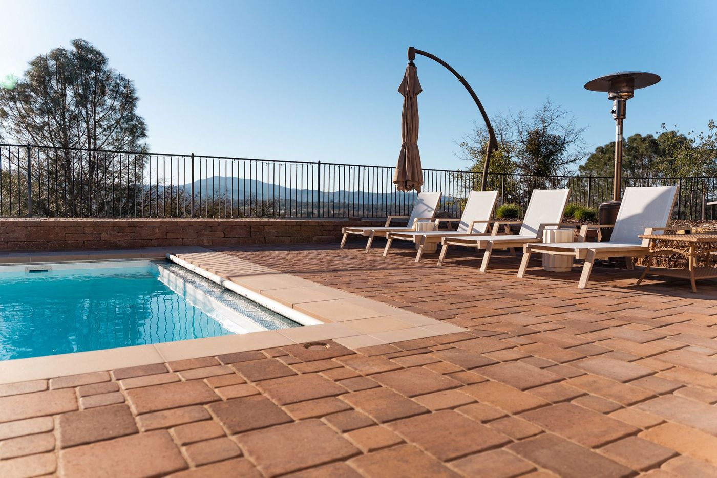 Upgraded pool deck in San Luis Obispo featuring modern lounge chairs, custom paver hardscape, and panoramic hillside views.