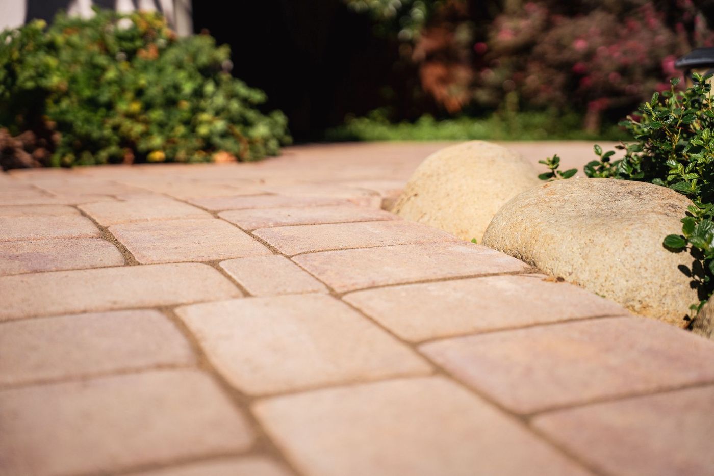 Close-up of interlocking paver walkway bordered with decorative river rocks in a San Luis Obispo landscape project.