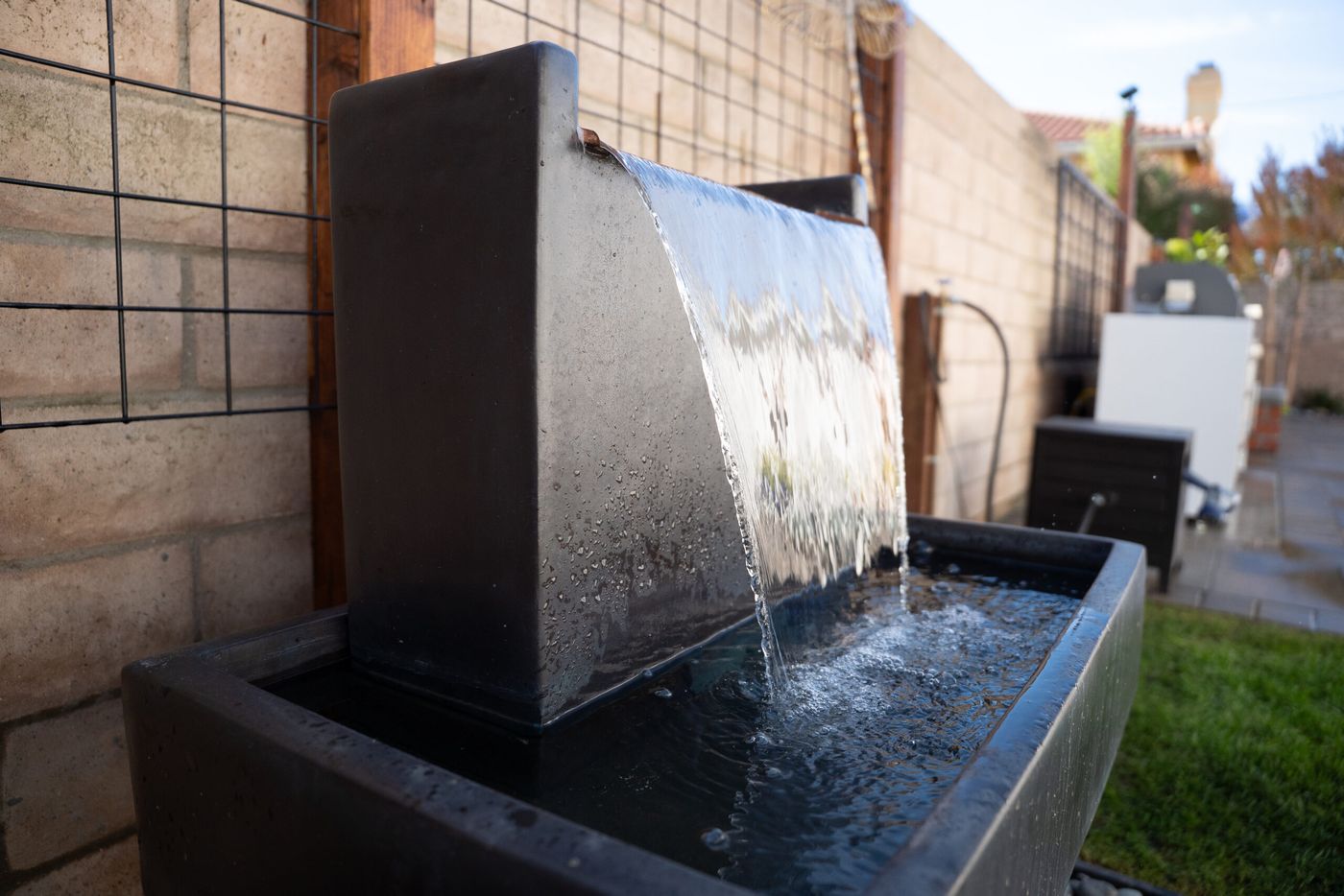 Close-up of cascading water flowing from a modern fountain feature in a Santa Maria side yard.
