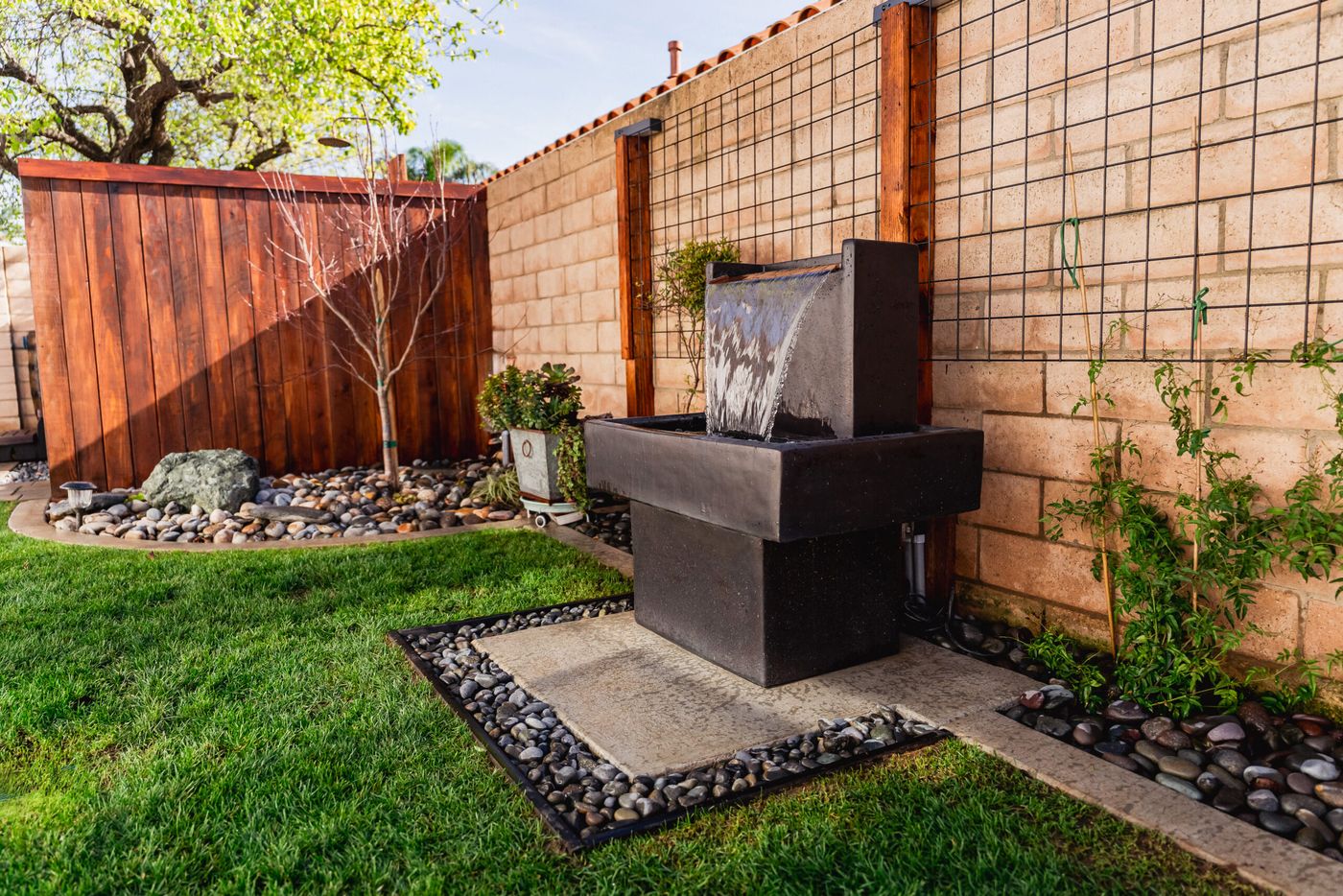 Contemporary black water feature fountain installed along a landscaped side yard in Santa Maria.