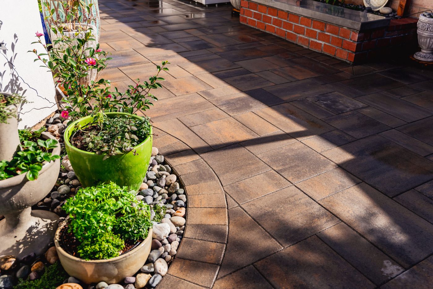 Close-up of textured paver patio with curved border and decorative planters in a Santa Maria side yard.