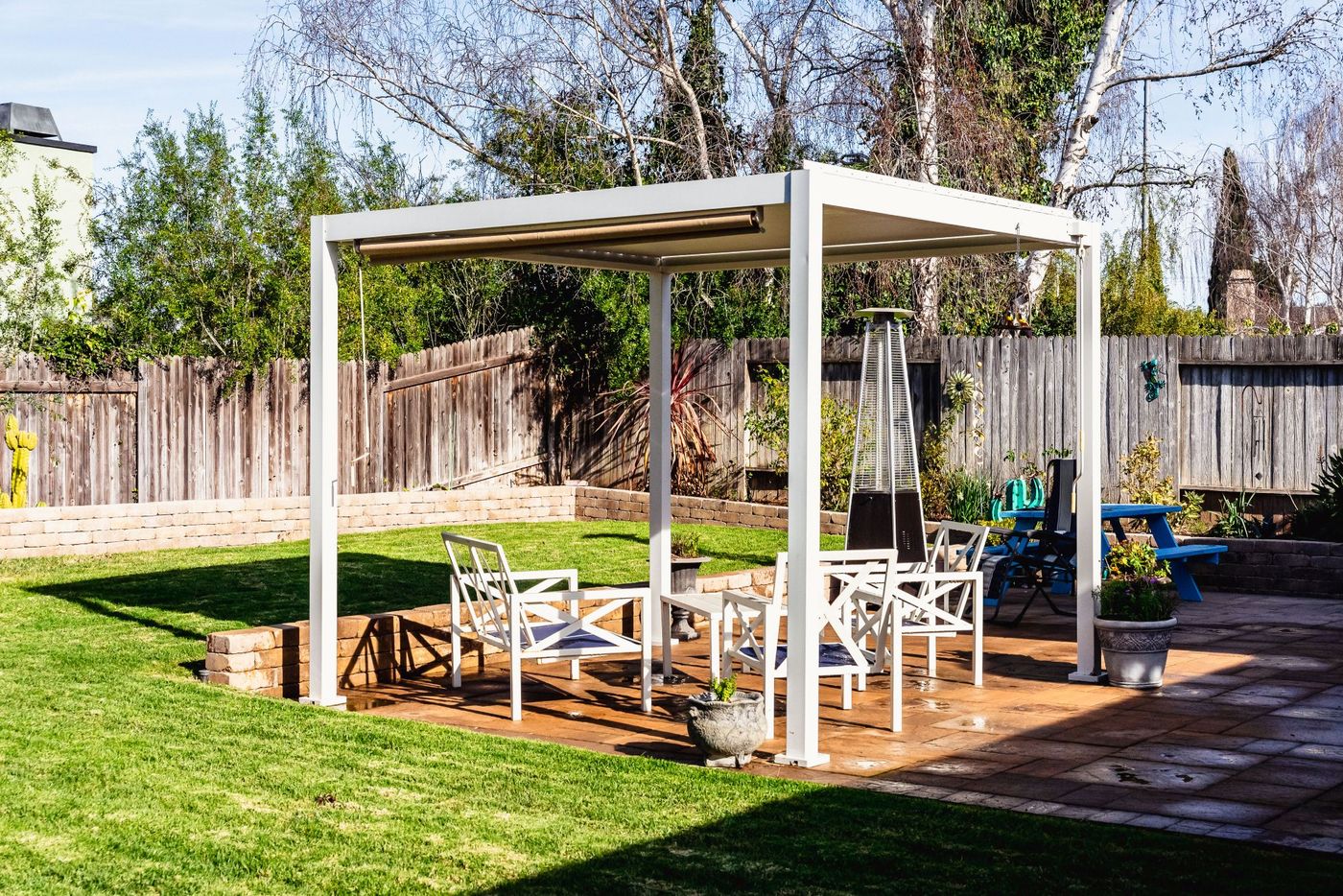 Freestanding white pergola covering a spacious paver patio with outdoor furniture in a Santa Maria residential backyard.