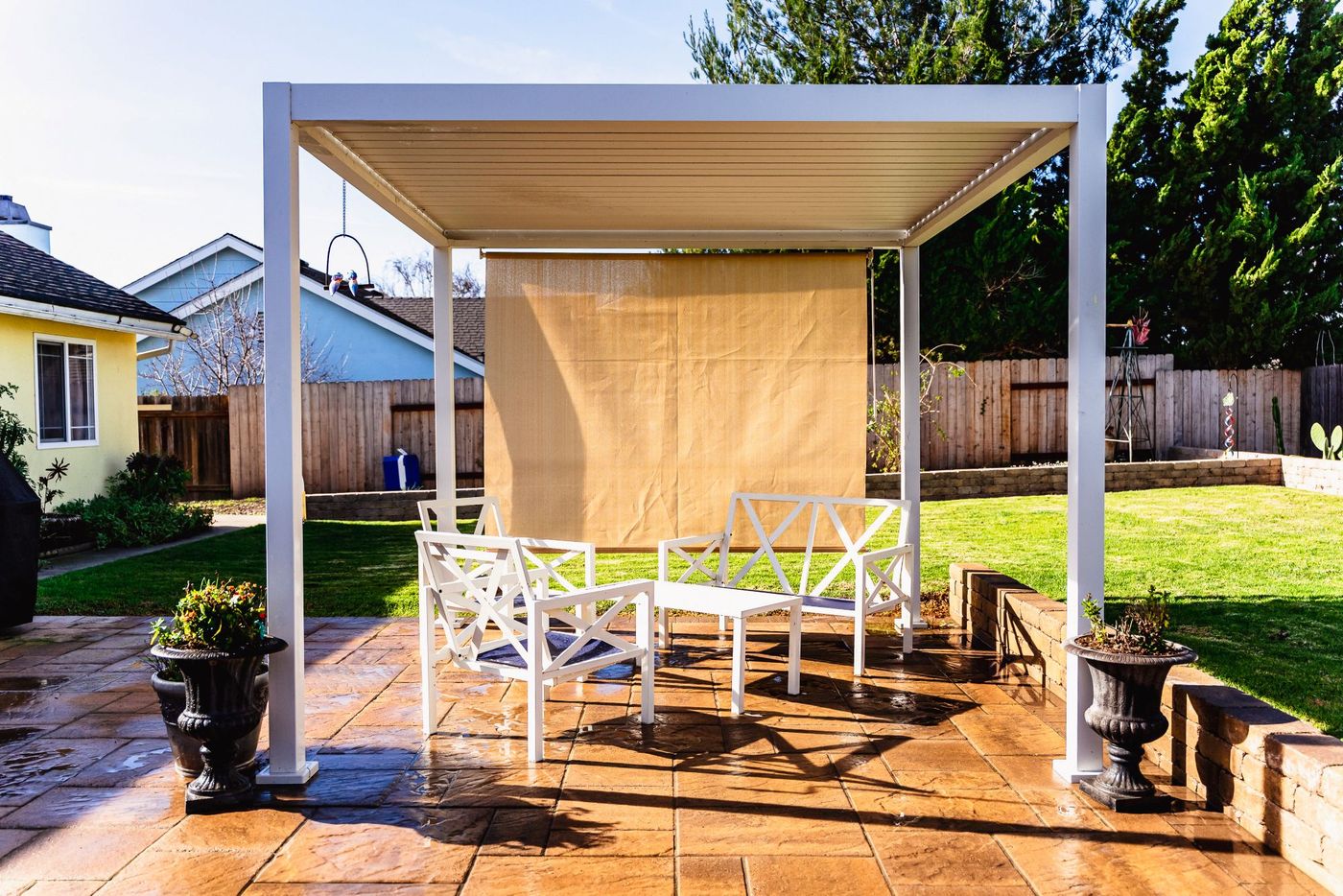 Modern white pergola installed over a custom paver patio with outdoor seating area in a Santa Maria backyard.