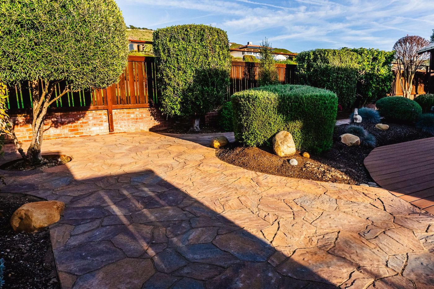 Custom stamped concrete walkway integrated with landscaped shrubs and decorative boulders in Shell Beach.
