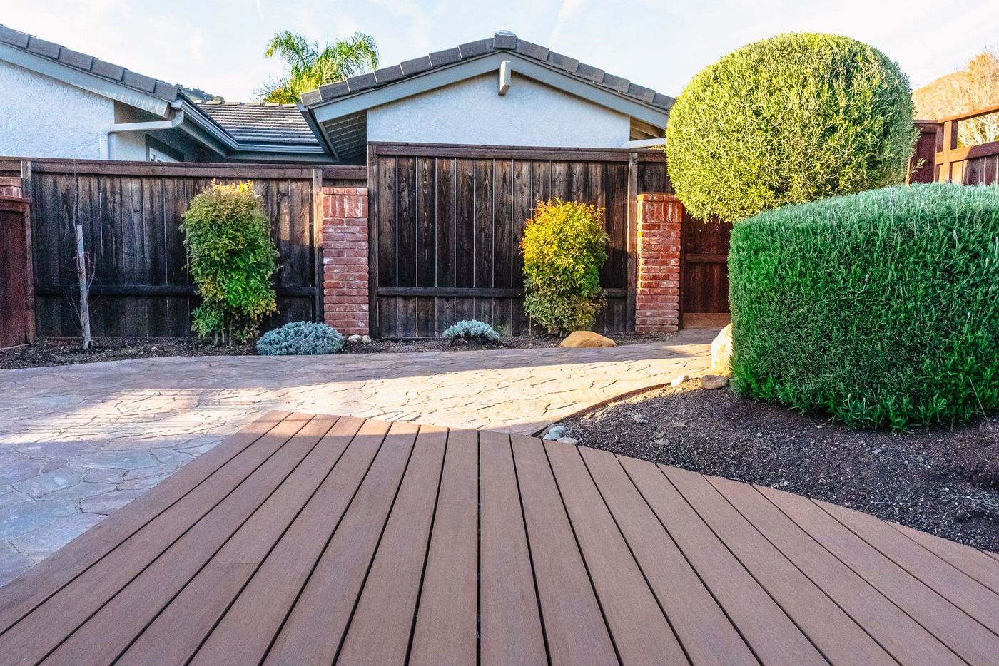 Stamped concrete walkway connecting to a composite deck area in a Shell Beach backyard landscape design.