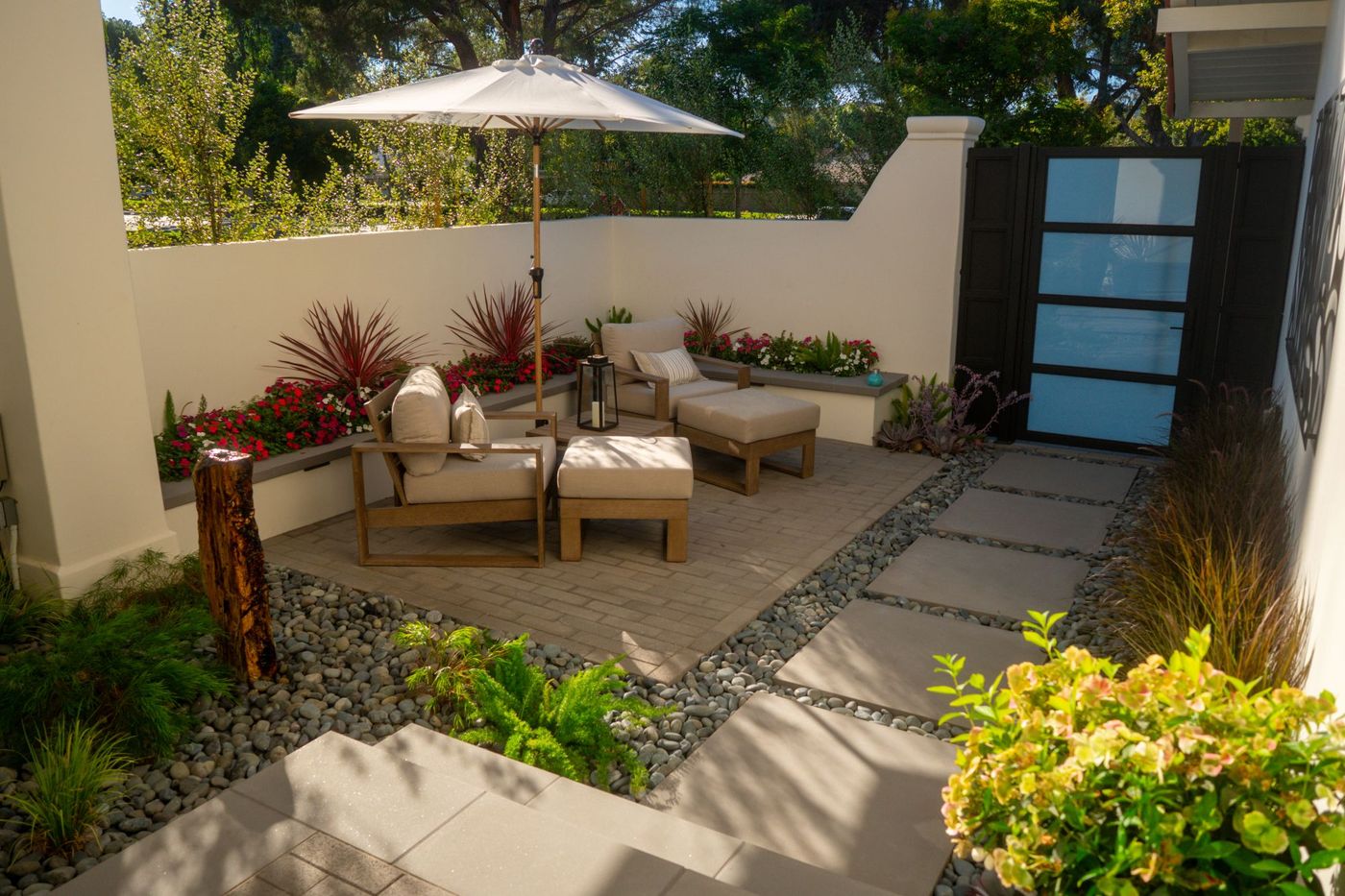 Compact backyard lounge space with patio chairs, planters, and stepping stone walkway in a modern landscape.