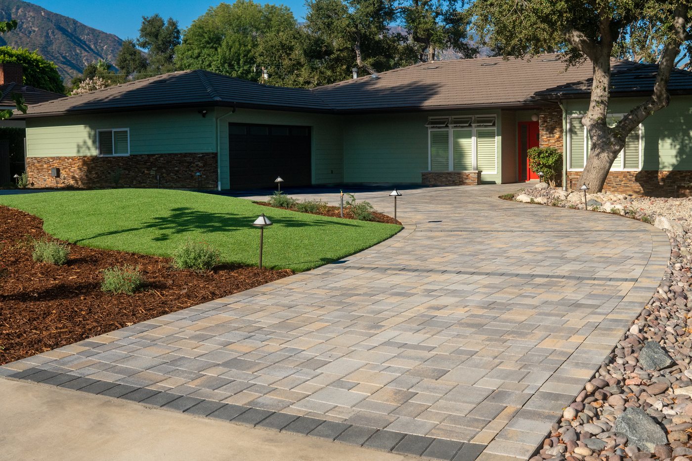 Curved paver driveway with a clean, consistent laying pattern leading to a ranch-style home