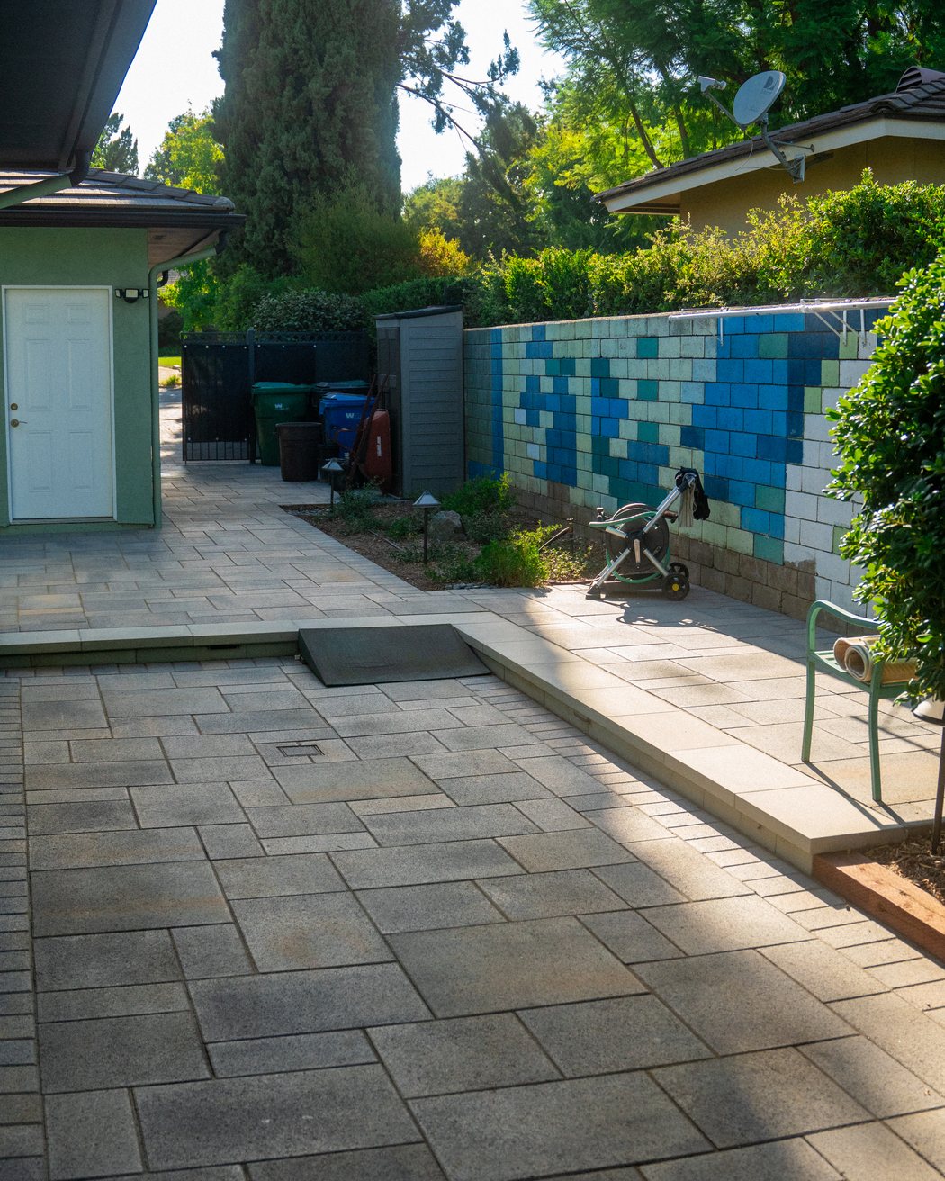 Paver walkway connecting a side entry door to a rear patio, matching the same paving material throughout