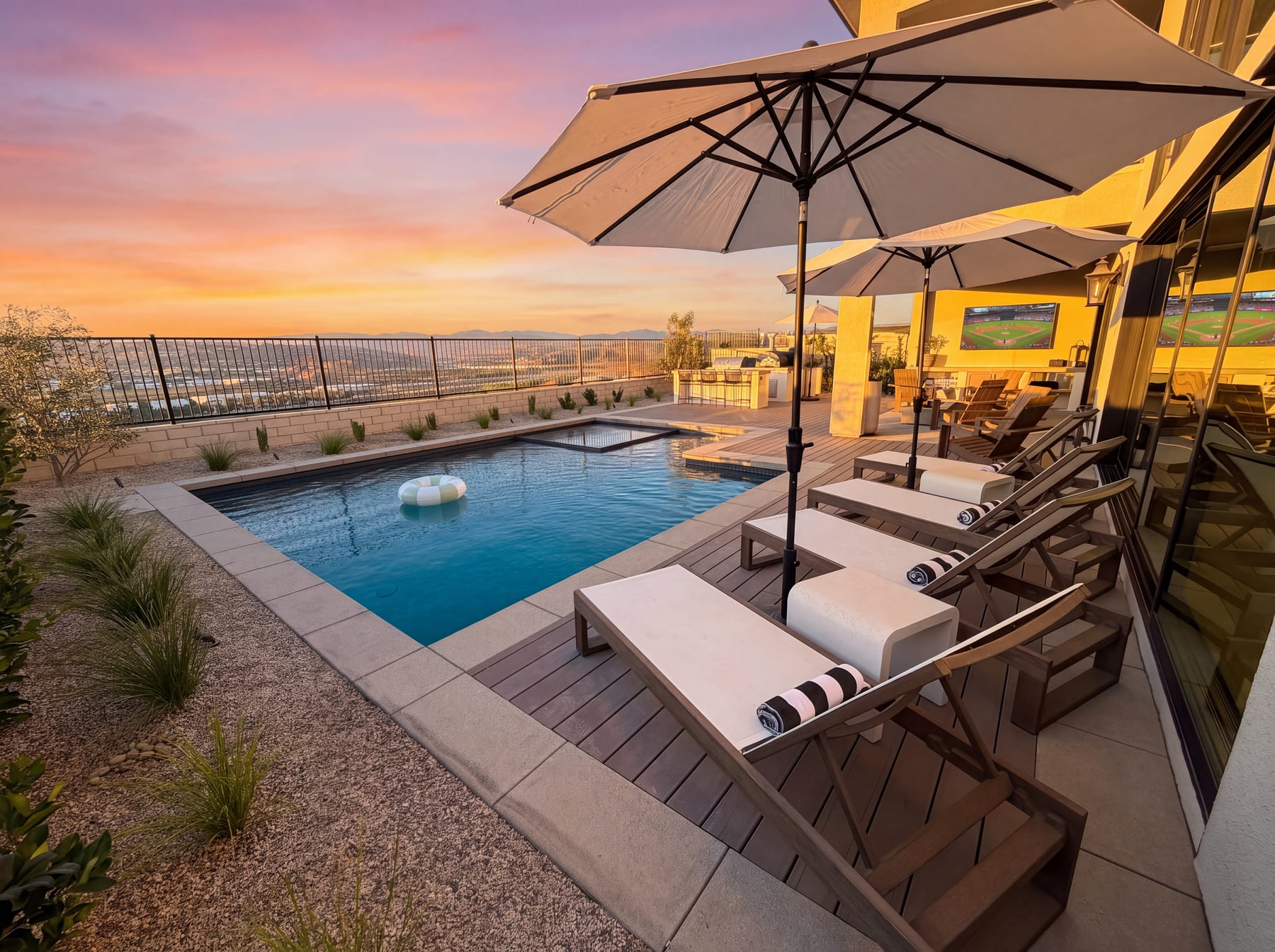 Hillside pool deck at sunset with lounge chairs, umbrellas, and an outdoor kitchen, Pacific Outdoor Living