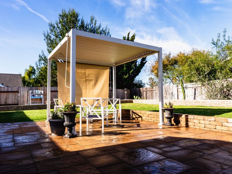 White pergola structure installed by a Santa Maria patio contractor over a custom paver patio with seating area.
