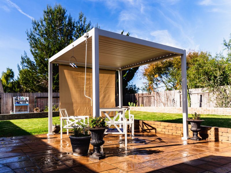White pergola structure installed by a Santa Maria patio contractor over a custom paver patio with seating area.