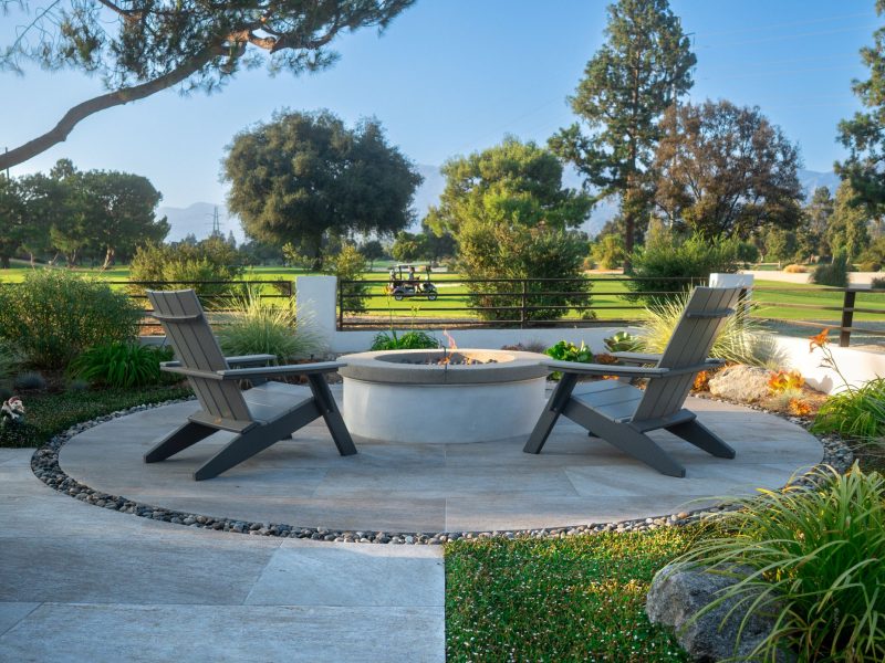 Symmetrical patio layout with central fire pit and lounge chairs facing a scenic golf course backdrop.