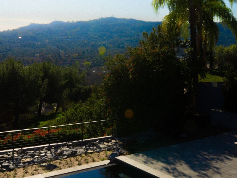 Raised backyard spa overlooking valley landscape and residential hillside scenery.