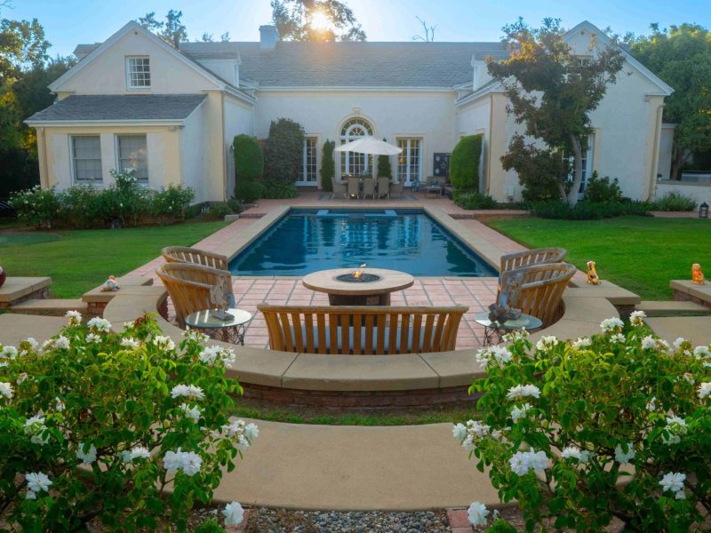 Luxury backyard swimming pool with fire pit seating and patio design by Pacific Outdoor Living