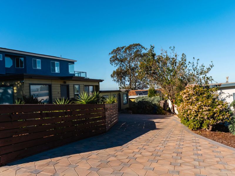 Curved paver driveway in Morro Bay bordered by decorative edging and coastal planting beds.