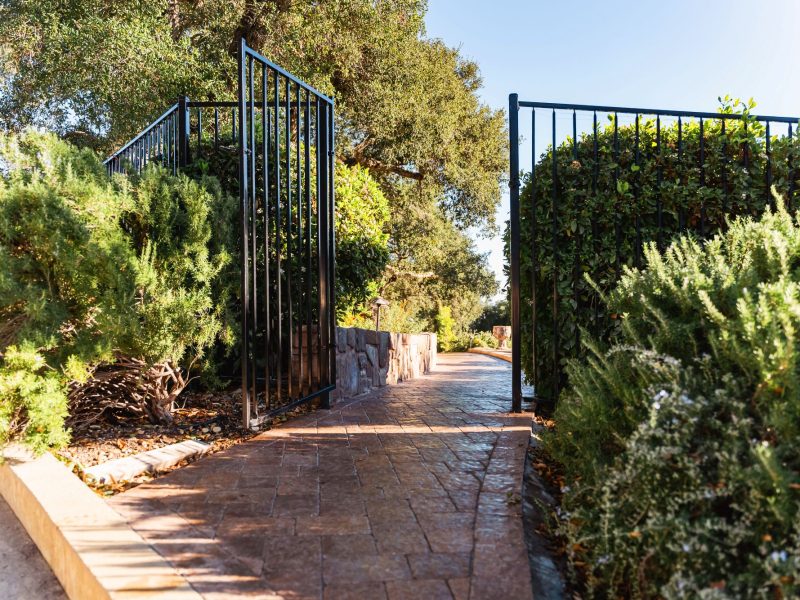 Decorative iron gate entrance opening to a stamped concrete paver walkway in Paso Robles, California.