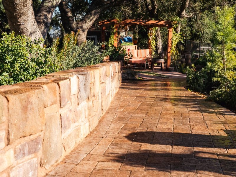 Stone retaining wall bordering a custom paver walkway in a landscaped Paso Robles outdoor living space.