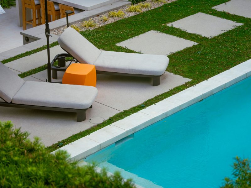 Detailed view of cushioned lounge chair beside a modern swimming pool and clean concrete decking.