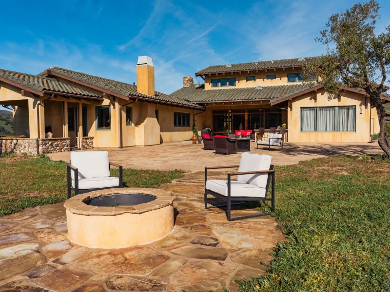 Stone patio fire pit installation in San Luis Obispo backyard with modern seating and hillside views.