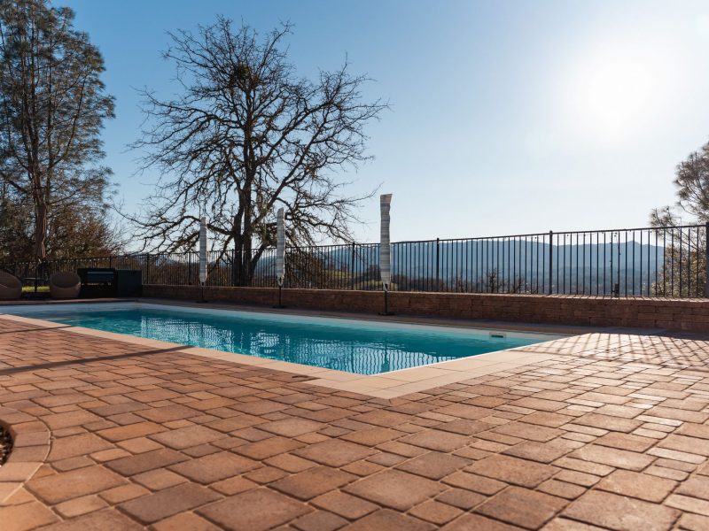Transformed backyard pool in San Luis Obispo featuring a custom paver deck and expansive hillside views.