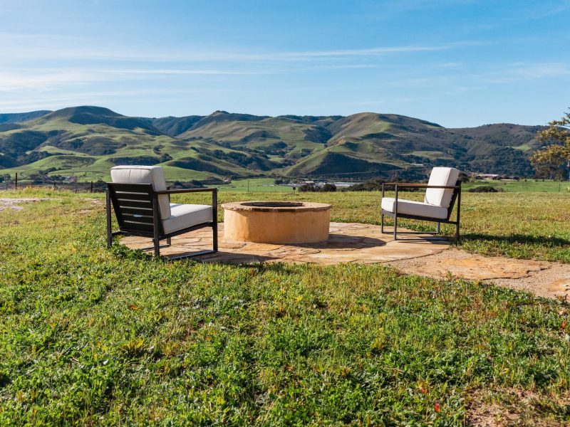 Outdoor fire pit seating area in San Luis Obispo overlooking rolling green hills and open landscape.