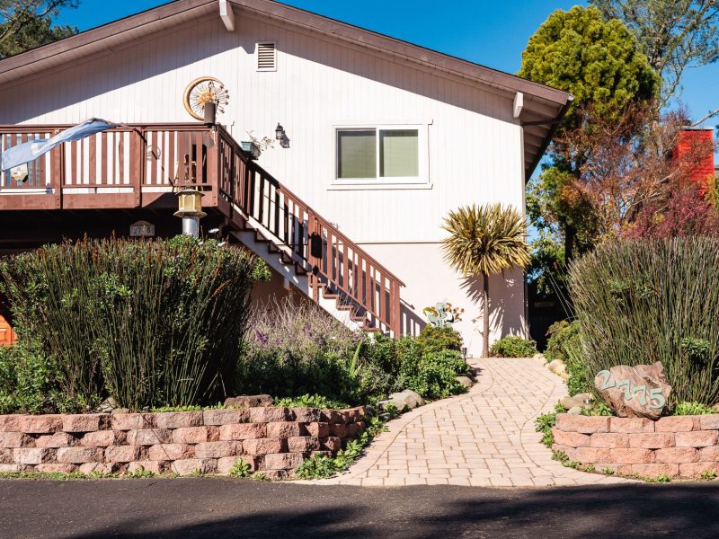 Front entry landscape in San Luis Obispo featuring a curved paver walkway, raised retaining walls, and lush planting beds.