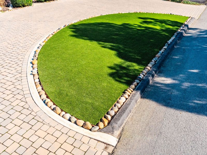 Water-efficient front yard landscape design in San Luis Obispo featuring artificial grass, curved concrete edging, and paver hardscape.