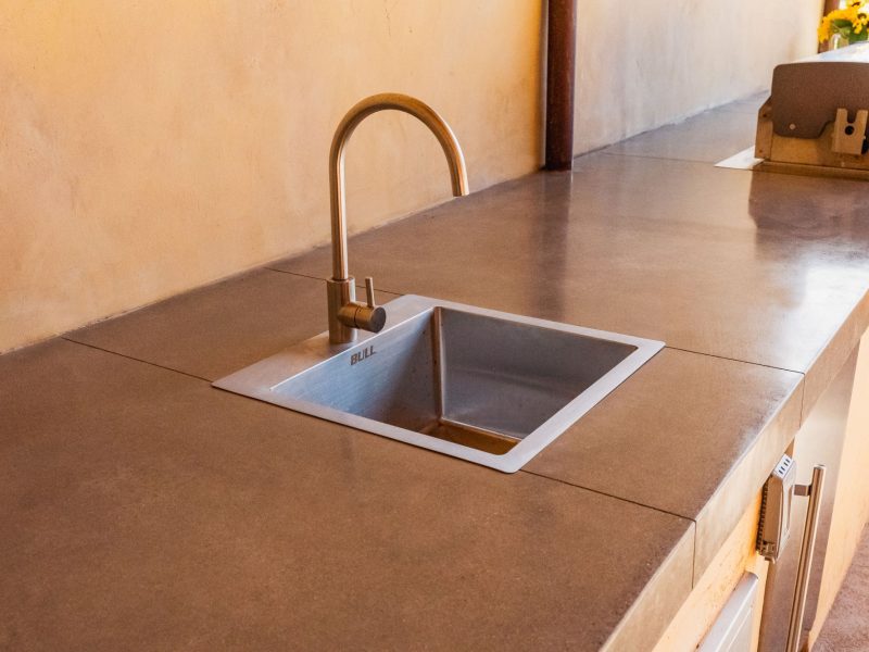 Close-up of outdoor kitchen sink and concrete countertop in a San Luis Obispo backyard entertainment space.