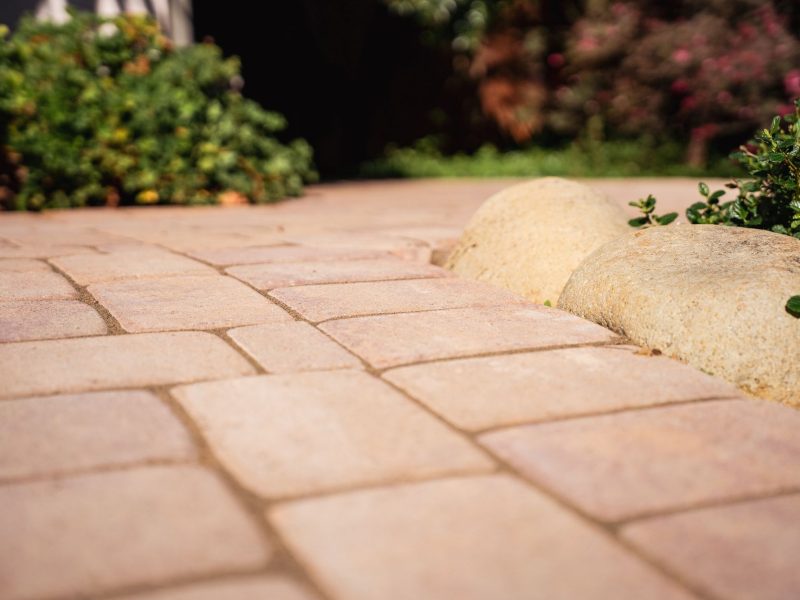 Close-up of interlocking paver walkway bordered with decorative river rocks in a San Luis Obispo landscape project.