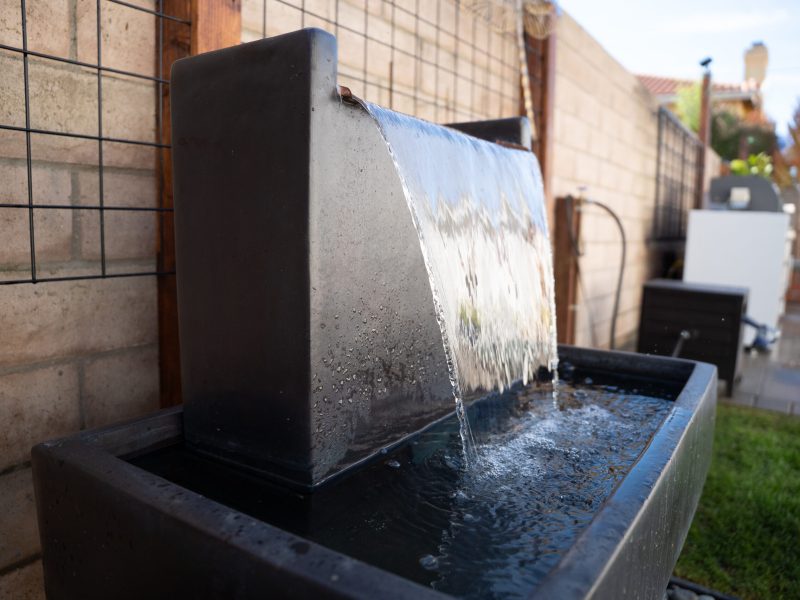 Close-up of cascading water flowing from a modern fountain feature in a Santa Maria side yard.