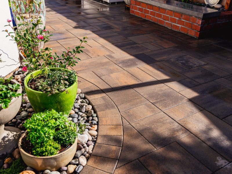 Close-up of textured paver patio with curved border and decorative planters in a Santa Maria side yard.