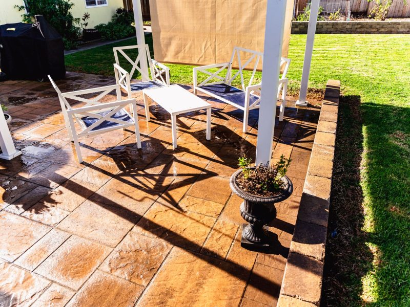 Outdoor seating arranged under a pergola on a textured paver patio in a Santa Maria backyard landscape design.
