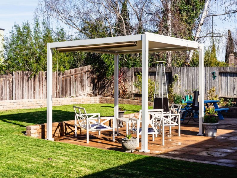 Freestanding white pergola covering a spacious paver patio with outdoor furniture in a Santa Maria residential backyard.