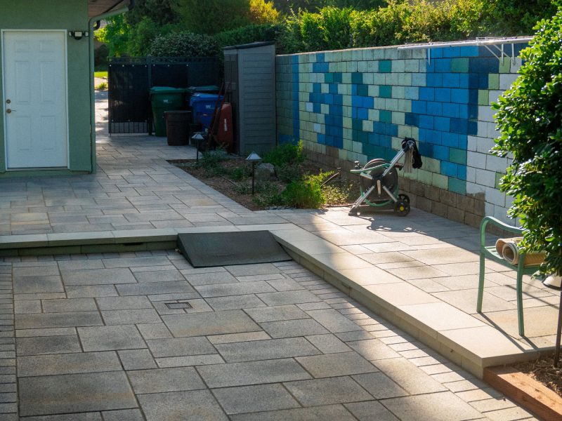 Modern side yard patio with large-format pavers and surrounding landscape elements forming a clean contemporary outdoor space.